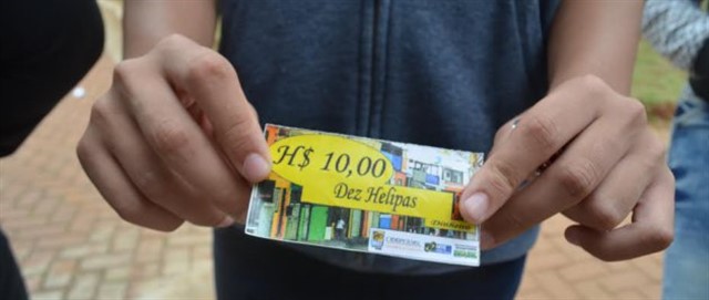 Jovem de Heliópolis mostra sua conta de $10 Helipas, moeda usada pela comunidade local nos negócios da vizinhança. Foto Katherine Jinyi Li / Plus55.