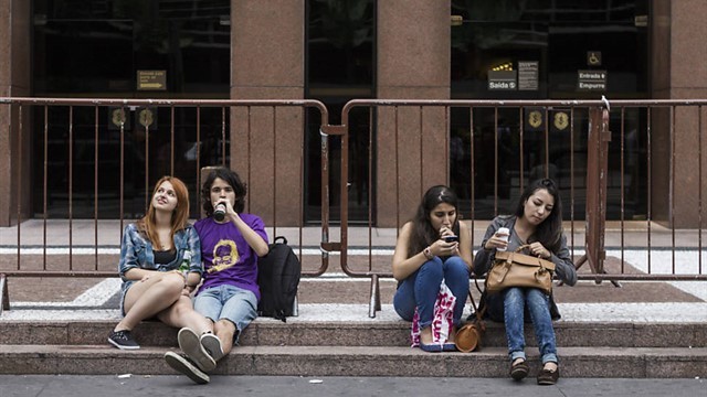 Pessoas sentam em escada em frente ao Banco Safra, na esquina da rua Augusta com a avenida Paulista, por falta de bancos no local. Foto: Pétala Lopes/Folhapress 